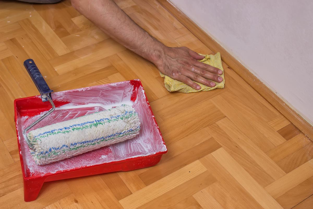 Muž čistící podlahu po malování